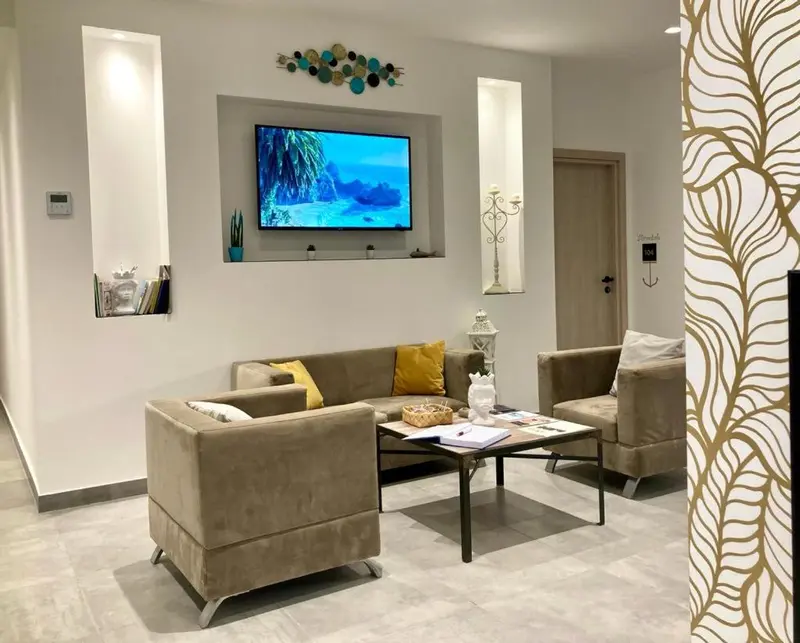 Un espace de détente avec canapés et table basse devant un téléviseur mural.