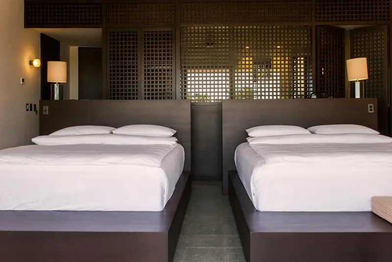 Deux lits simples avec des draps blancs dans une chambre moderne.