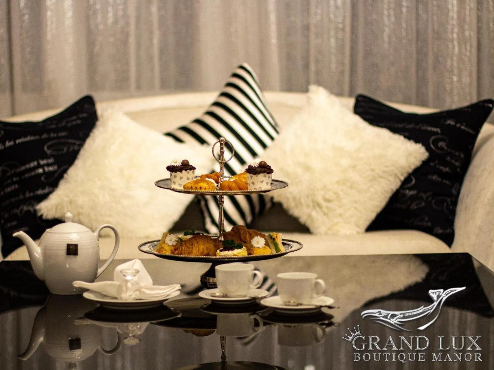 Une table basse présente une théière, une pyramide de pâtisseries et des tasses à thé.