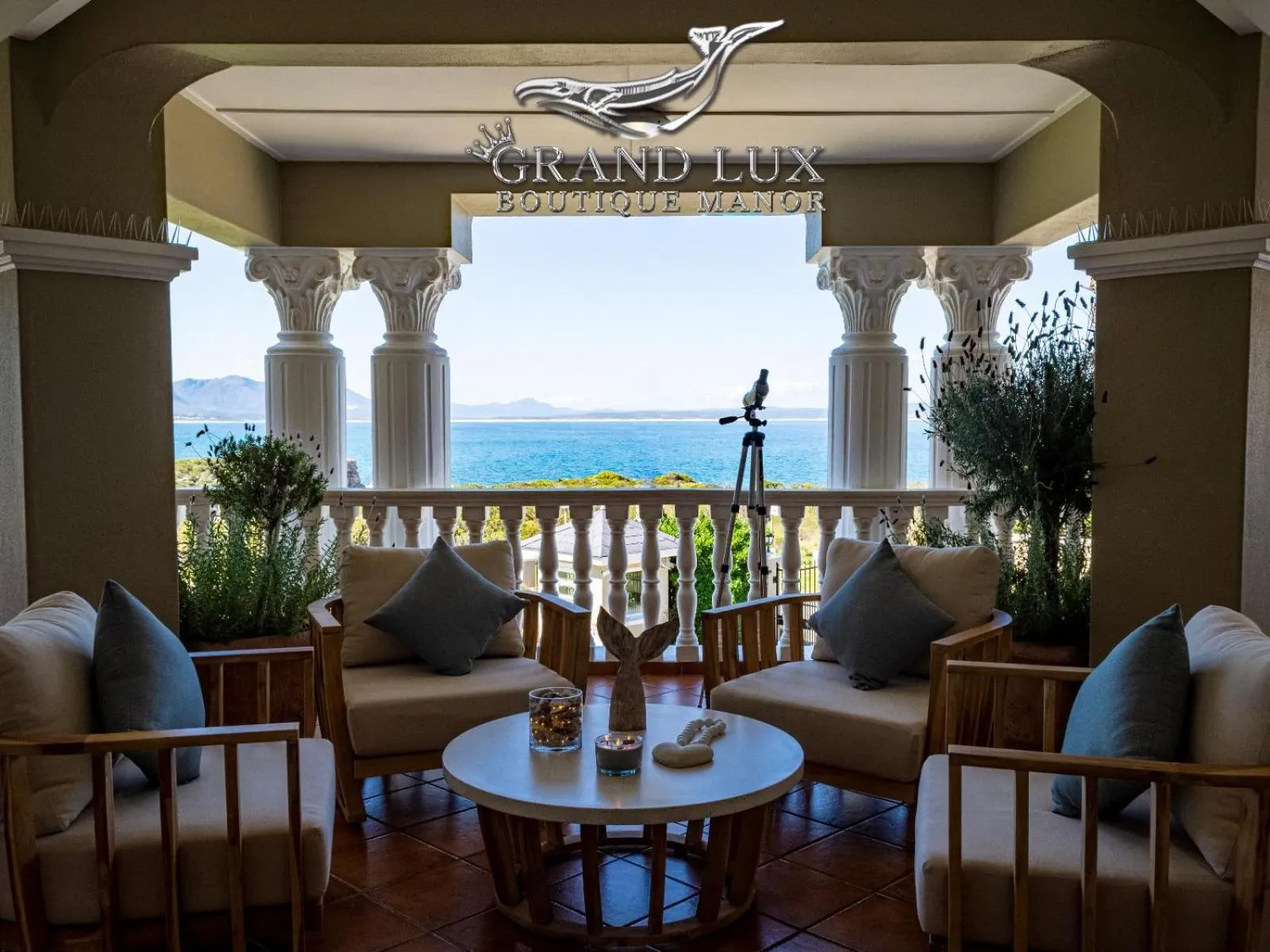 Espace de détente extérieur avec mobilier en bois et vue sur la mer.