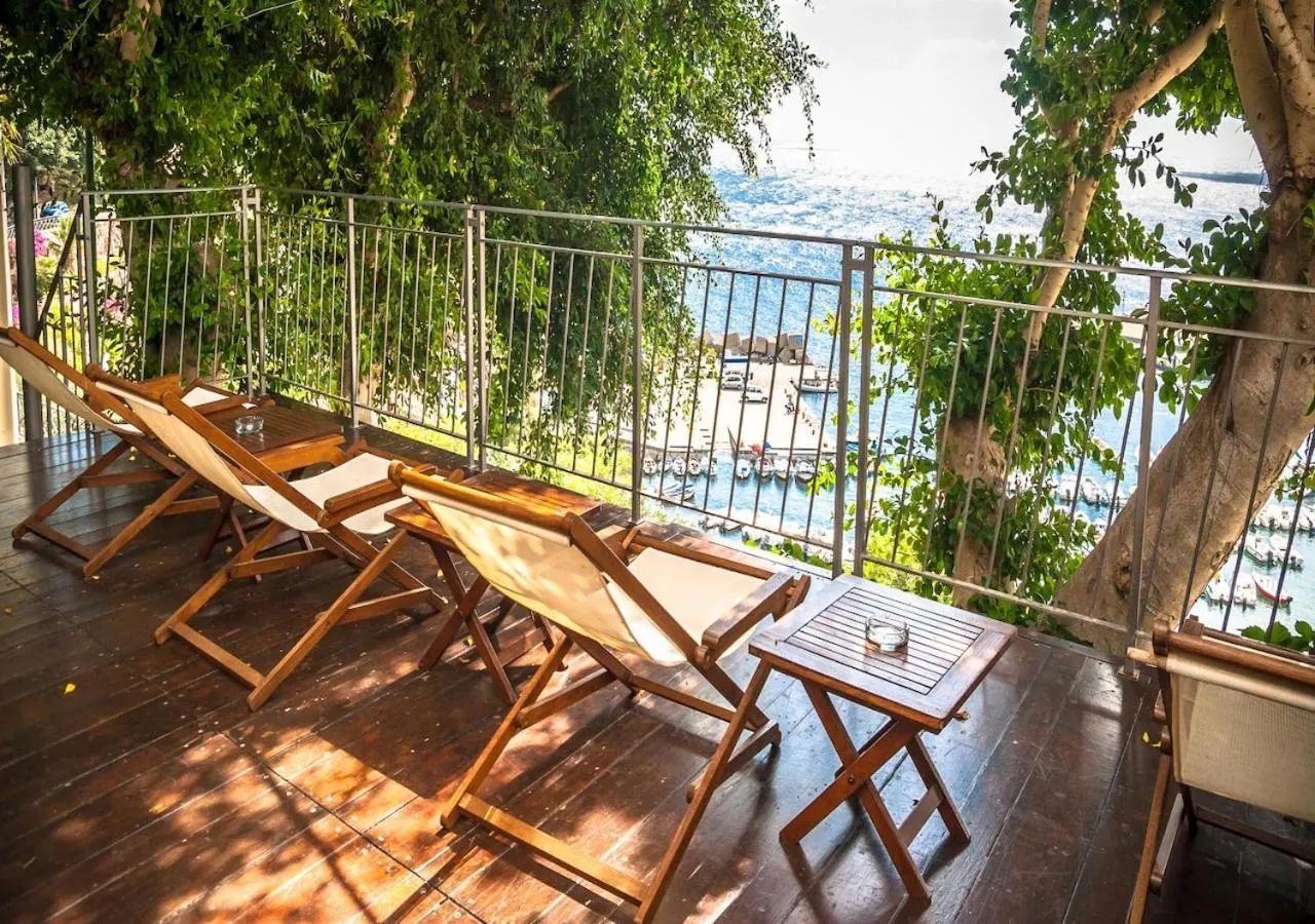 Terrasse en bois avec chaises longues et vue sur la mer.