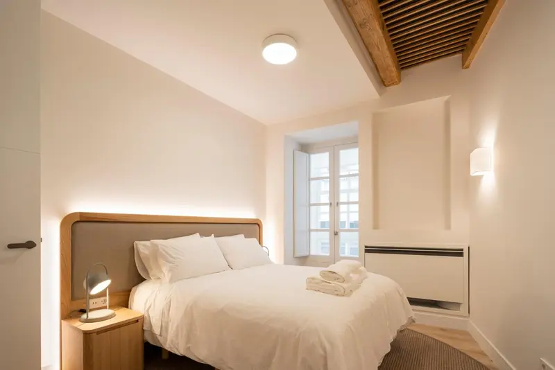 Une chambre lumineuse avec un lit double et une fenêtre.