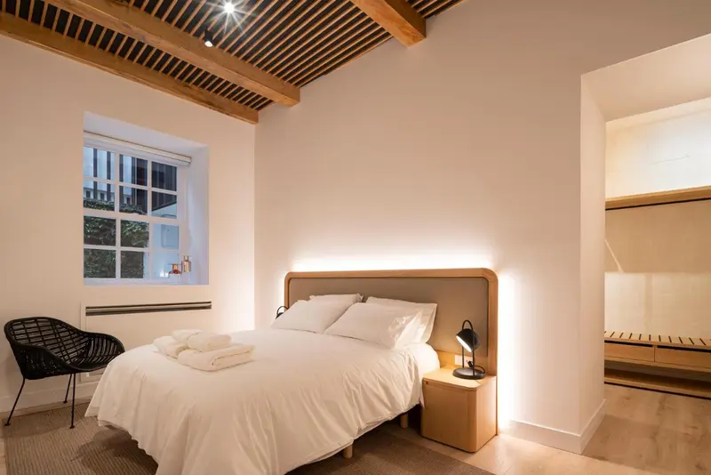 Une chambre lumineuse avec un lit recouvert d'une courtepointe blanche et un éclairage indirect.