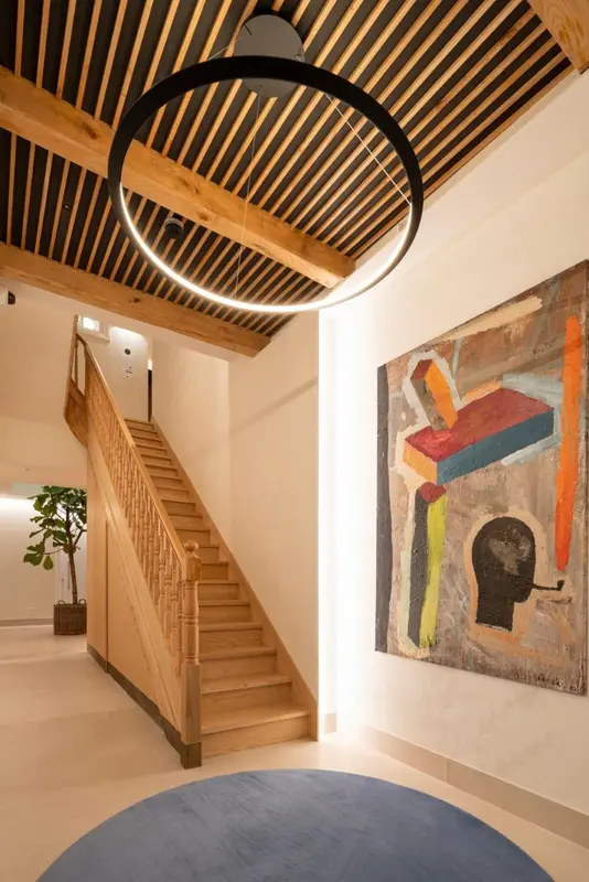 Un escalier en bois mène à l'étage supérieur dans un hall lumineux.