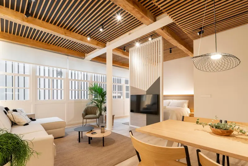 Espace de vie lumineux avec canapé, table basse et salle à manger.
