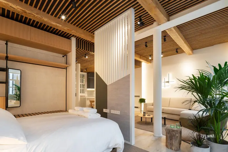 Une chambre lumineuse avec un lit fait et une décoration moderne.