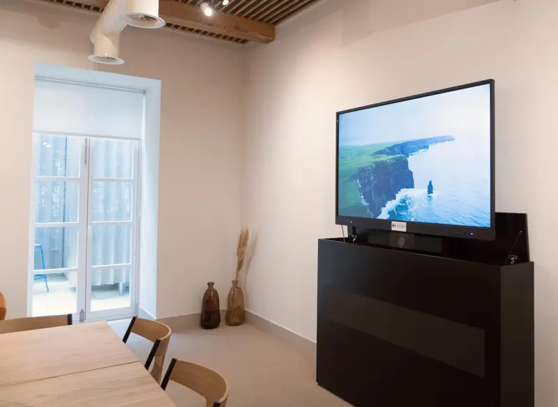 Une pièce lumineuse avec une télévision accrochée au mur et une table à manger en bois.