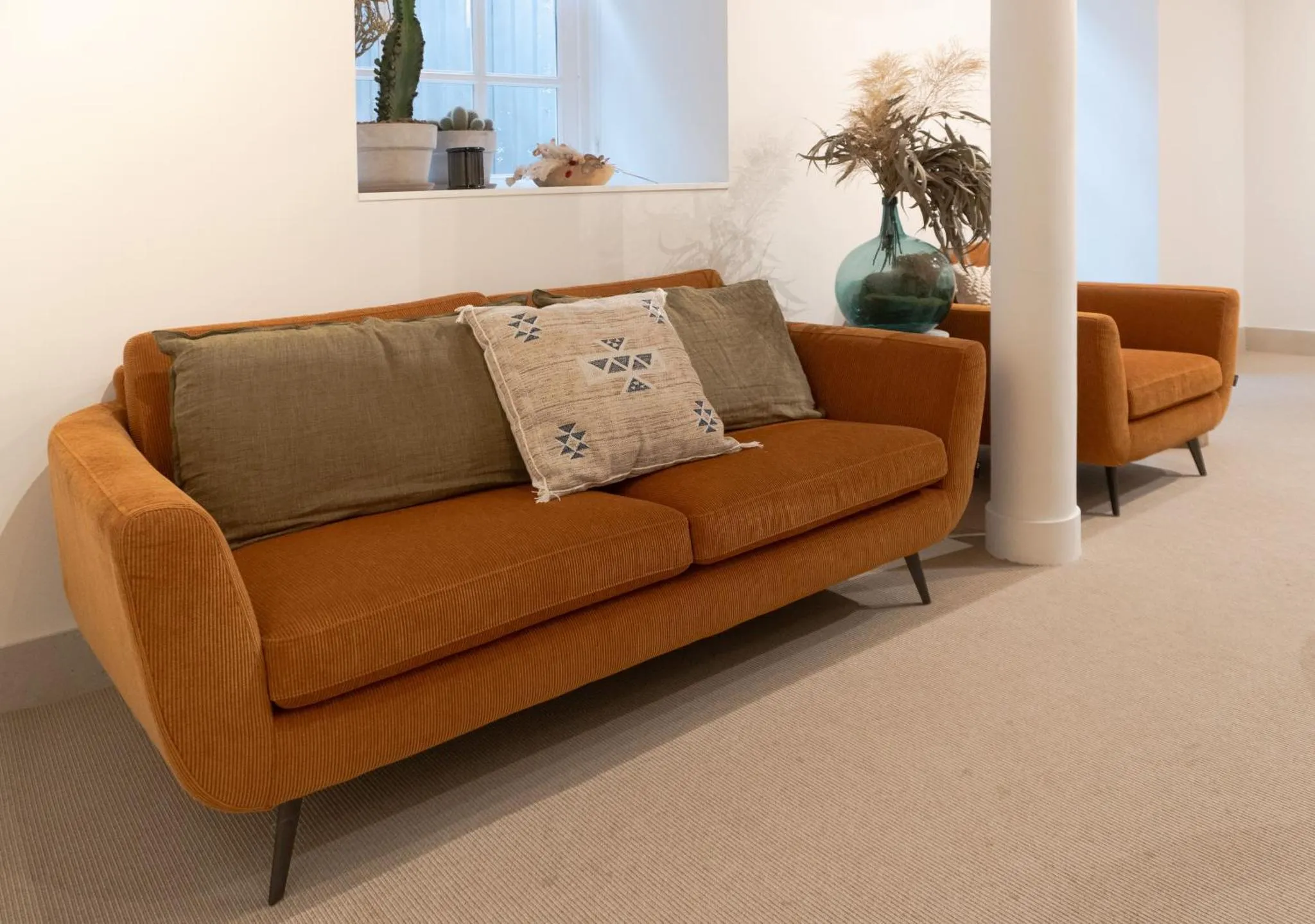 Un canapé orange et deux fauteuils dans un espace de détente.