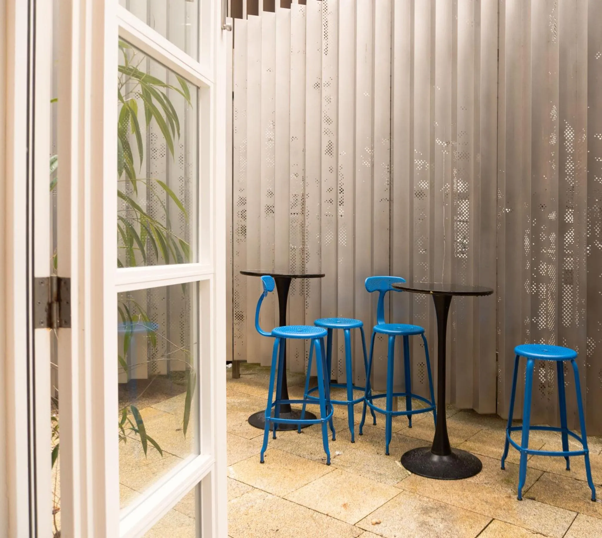 Petites tables bleues et tabourets hauts dans un espace lumineux.
