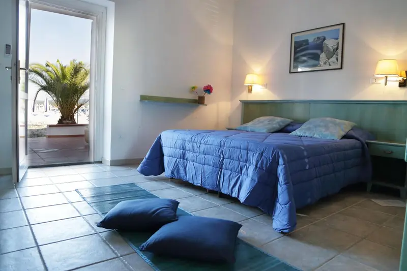 Une chambre lumineuse avec un lit fait et un accès à une terrasse.