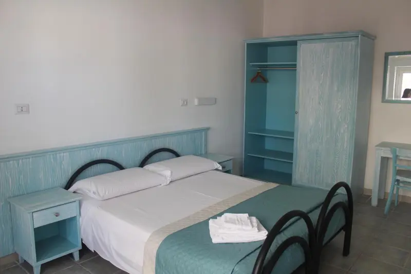 Une chambre lumineuse avec un lit double et une armoire.
