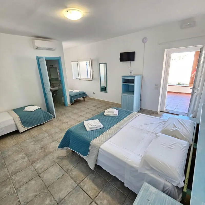 Une chambre lumineuse avec deux lits et une porte ouverte sur une terrasse.