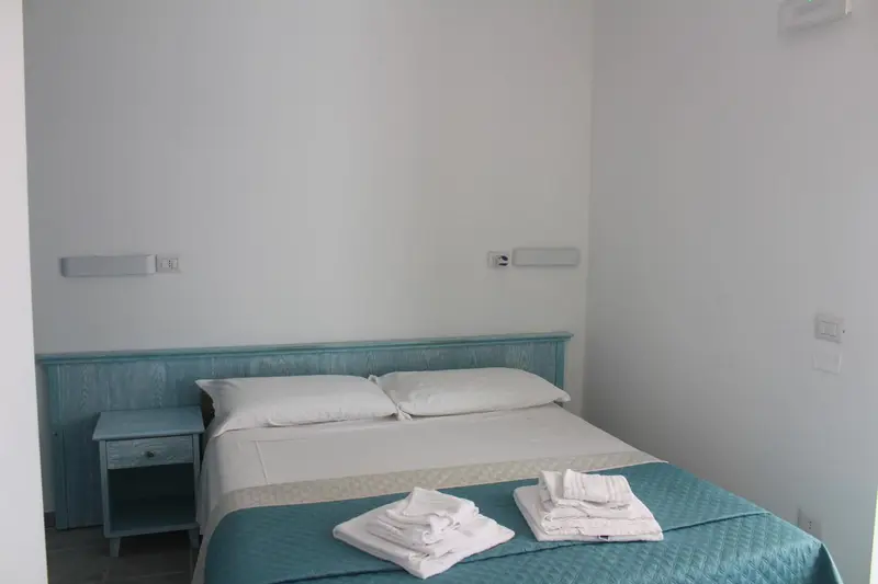 Une chambre lumineuse avec un lit double et une table de chevet.