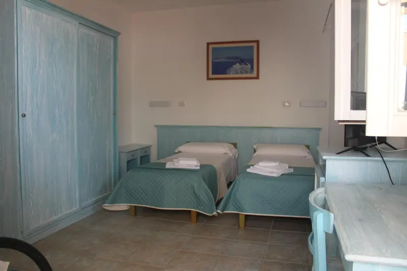 Une chambre lumineuse avec deux lits simples et une armoire.