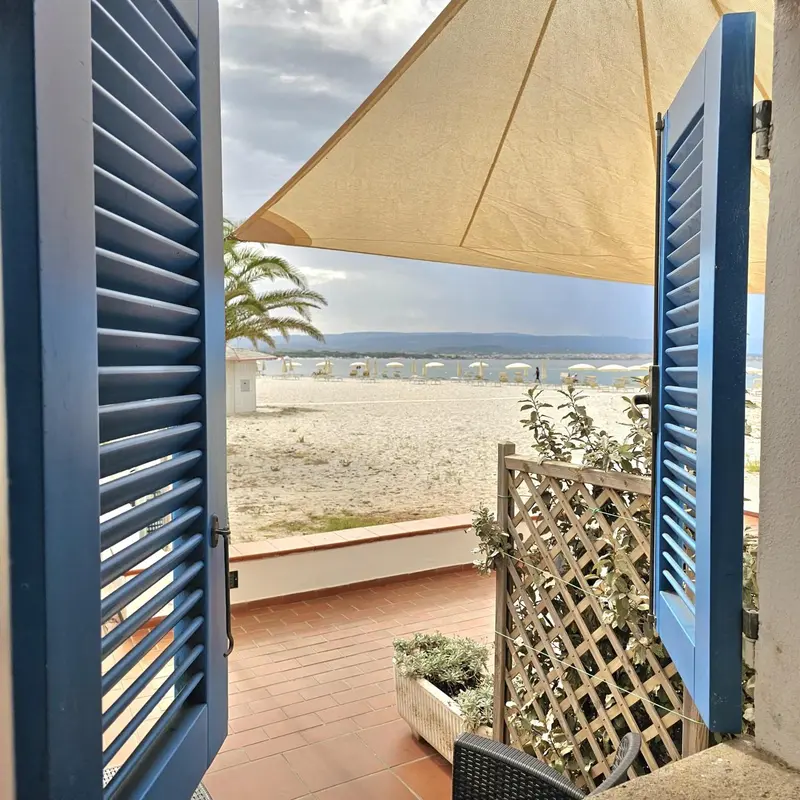 Vue sur une plage ensoleillée depuis une terrasse ombragée.