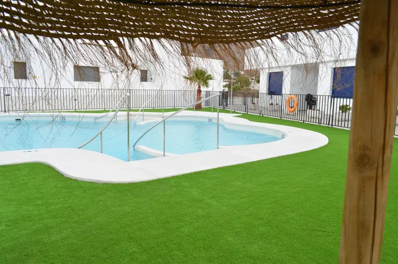 Une piscine rectangulaire avec des marches et une bordure en gazon synthétique.