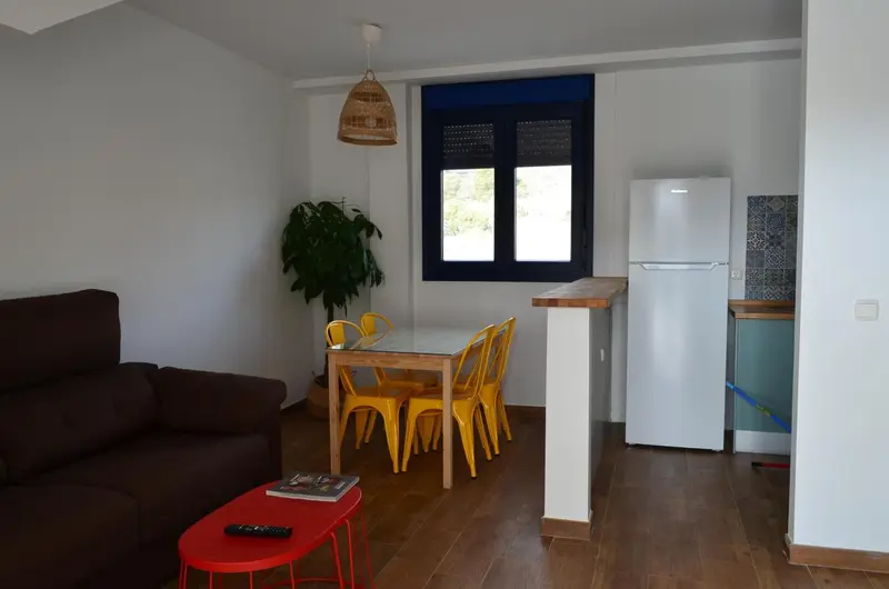 Espace de vie lumineux avec canapé, table à manger et kitchenette.
