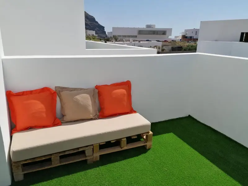 Canapé d'extérieur avec coussins sur une terrasse en gazon synthétique.