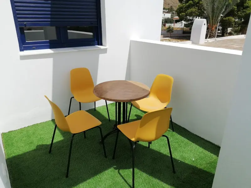 Une table ronde jaune et quatre chaises sont disposées sur une pelouse artificielle.
