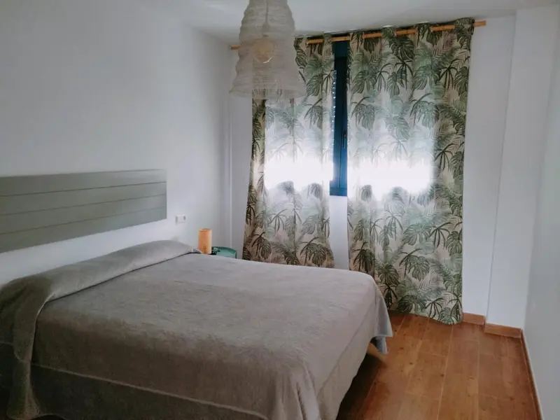 Une chambre lumineuse avec un lit fait et des rideaux à motifs.