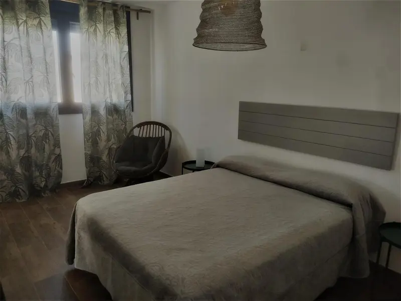 Une chambre lumineuse avec un grand lit et un fauteuil.