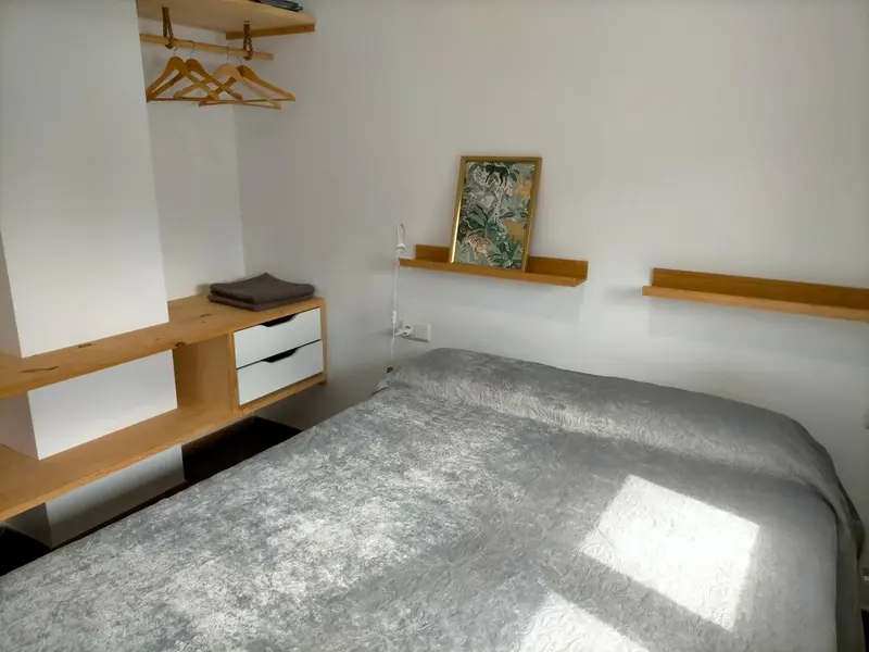 Une chambre lumineuse avec un lit simple et des étagères murales.
