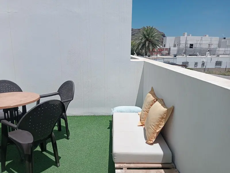 Terrasse aménagée avec mobilier de jardin et coussins.
