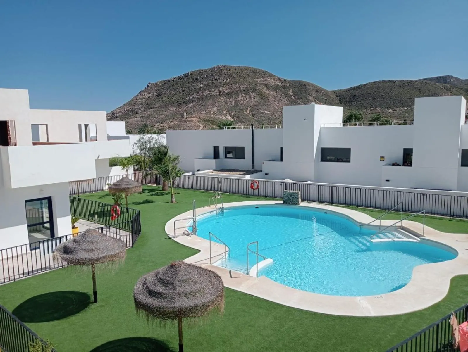 Une piscine rectangulaire avec un espace de détente ombragé.