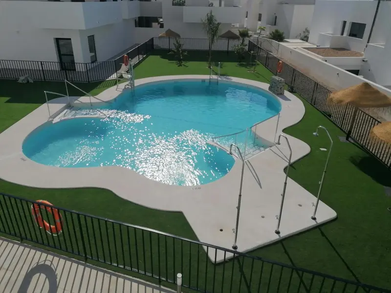 Une piscine rectangulaire avec des marches et un espace vert artificiel.