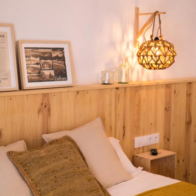Une chambre lumineuse avec un lit recouvert de coussins et une tête de lit en bois.