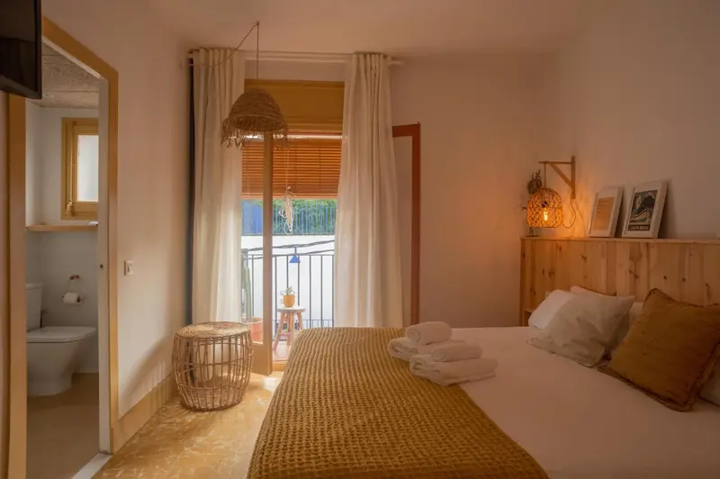 Une chambre lumineuse avec un lit recouvert d'une couverture jaune et un accès à un balcon.