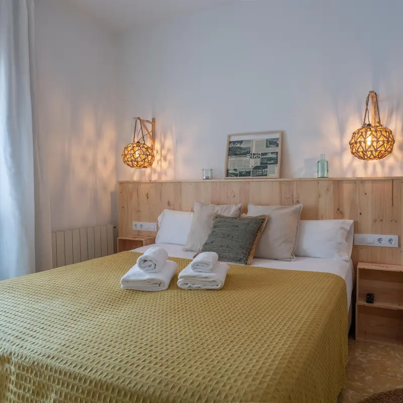 Une chambre lumineuse avec un grand lit recouvert d'une couverture jaune et de plusieurs oreillers.
