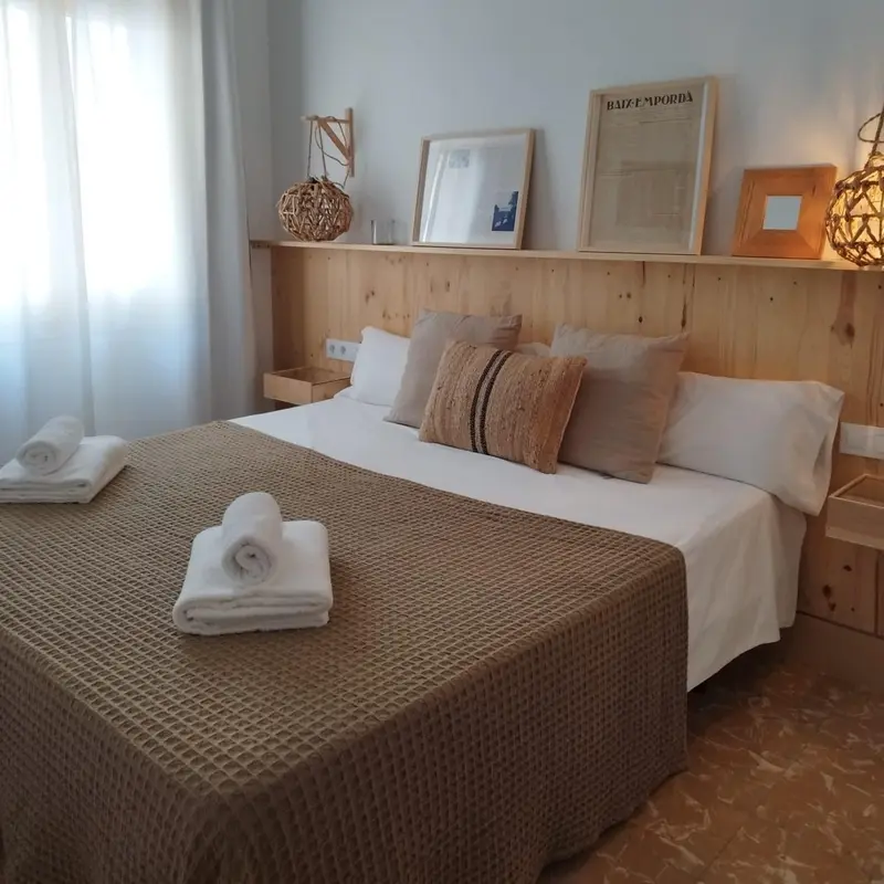 Une chambre lumineuse avec un grand lit recouvert d'une courtepointe et de coussins.