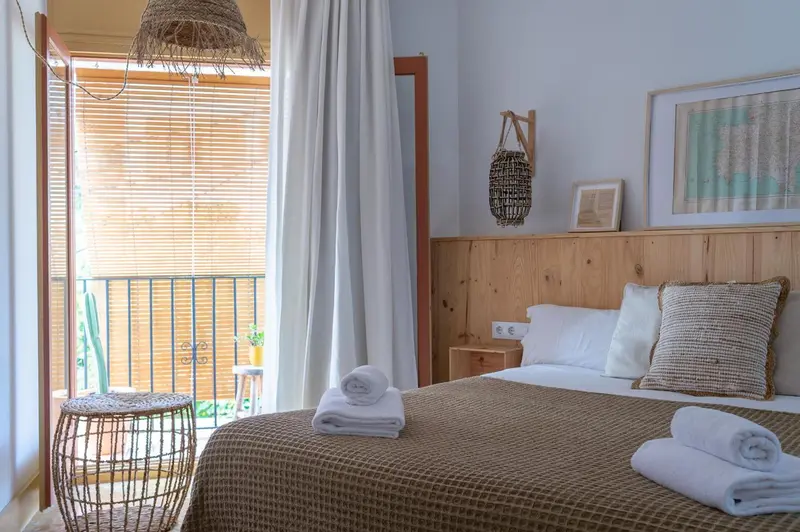 Une chambre lumineuse avec un lit double et un accès à une terrasse.