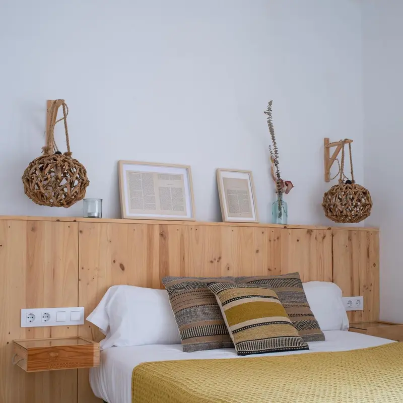 Un lit avec des oreillers et une couverture jaune dans une chambre décorée de bois et d'objets artisanaux.