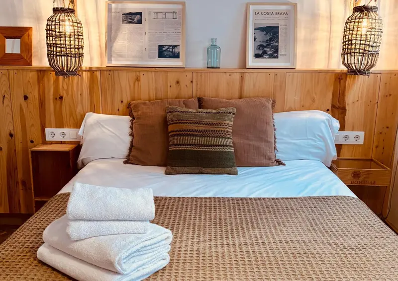 Un lit double avec des oreillers et des coussins blancs dans une chambre au décor en bois.