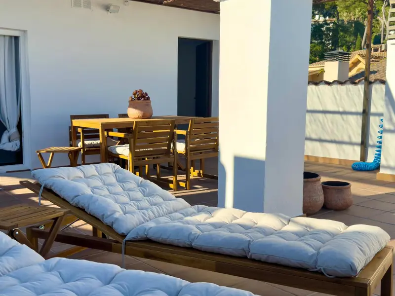 Terrasse avec mobilier de détente et table à manger en bois.