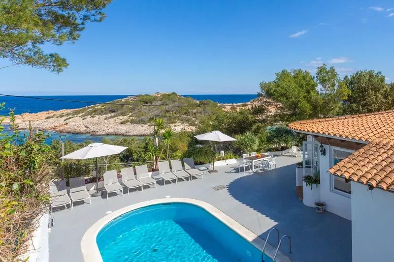 Terrasse avec transats et piscine face à la mer.