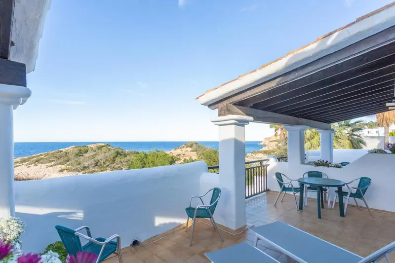 Terrasse carrelée avec mobilier de jardin et vue sur la mer.