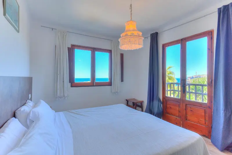Une chambre lumineuse avec un lit blanc et une vue sur la mer.