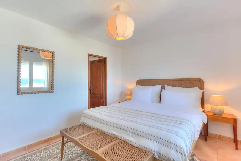 Une chambre lumineuse avec un lit recouvert d'une courtepointe blanche.