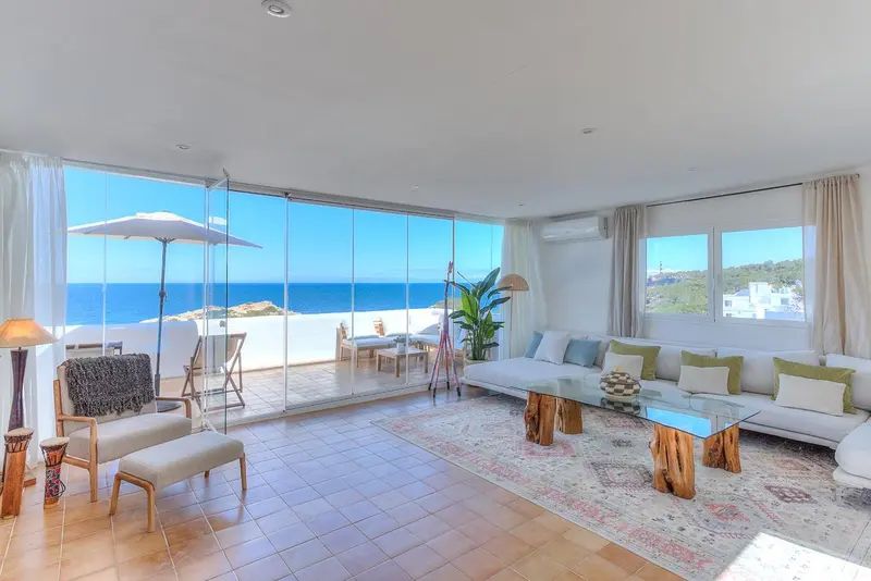 Espace de séjour lumineux avec vue sur la mer depuis de grandes baies vitrées.
