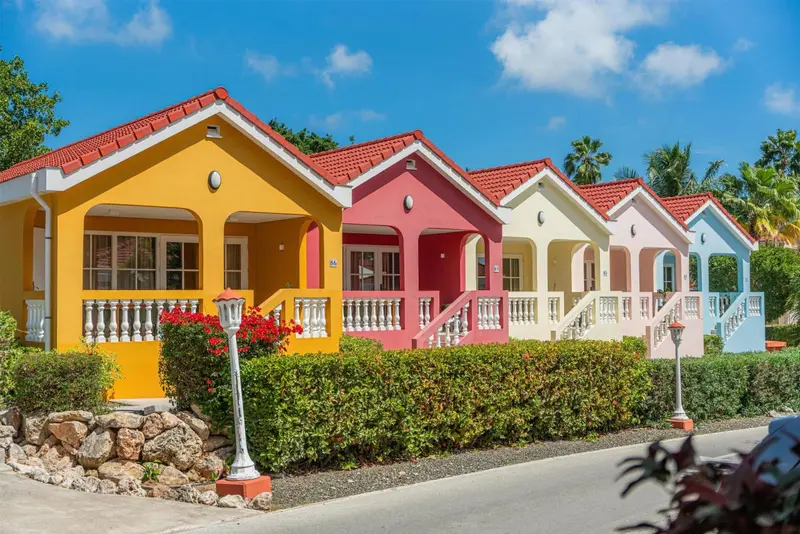 Alignée de maisons colorées avec des toits rouges et des jardins fleuris.