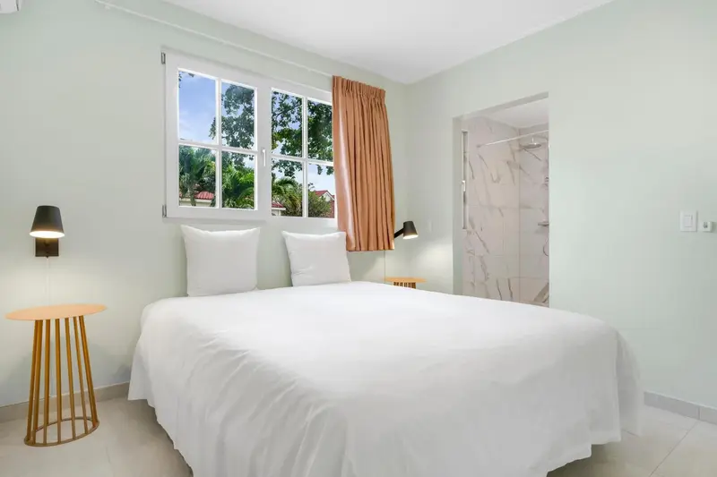 Une chambre lumineuse avec un grand lit et une salle de bain moderne.