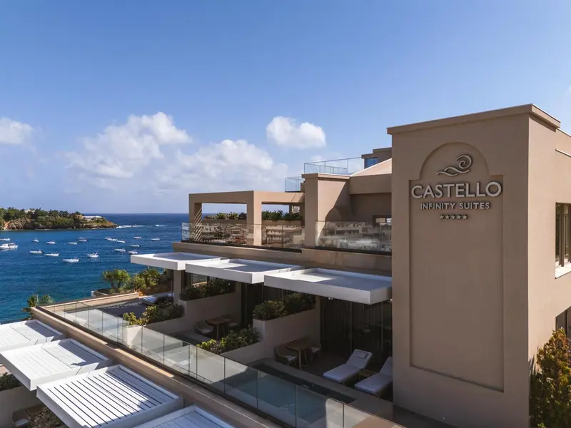 Vue aérienne d'un bâtiment beige avec des balcons et une piscine surplombant la mer.