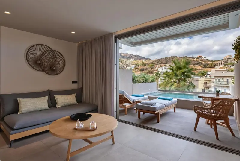 Un espace de séjour lumineux s'ouvre sur une terrasse avec piscine et vue sur la végétation.