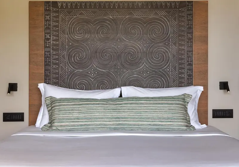 Un lit double avec une tête de lit en bois sculptée et des oreillers blancs.
