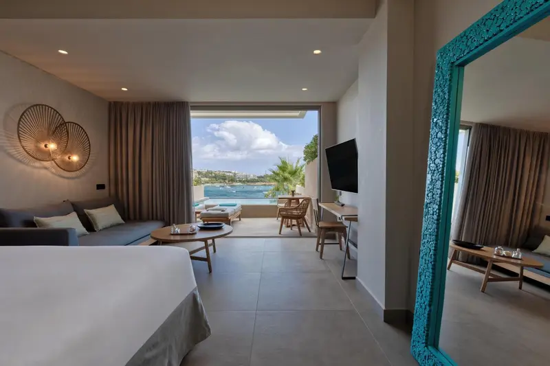 Espace de vie lumineux avec canapé, lit et vue sur la mer.