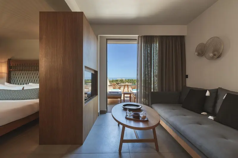 Espace de vie intérieur avec canapé et accès à une terrasse ensoleillée.