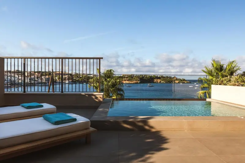 Terrasse avec transats et petite piscine offrant une vue sur la mer et la côte.